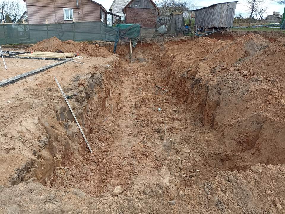 Выкопанная траншея в песчаном грунте под опорную часть стены